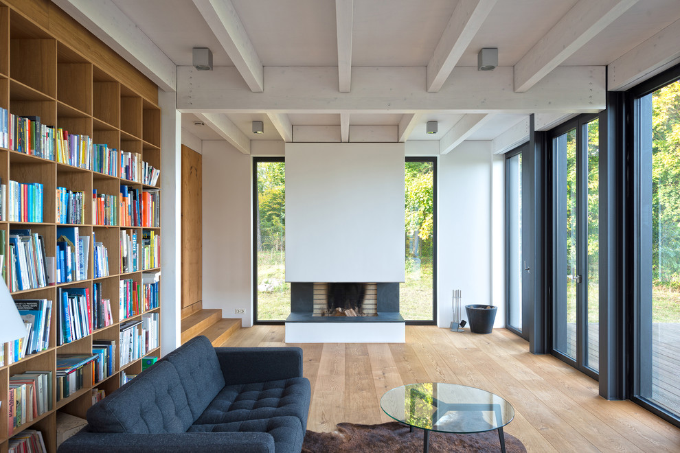 Abgetrennte, Mittelgroße Moderne Bibliothek mit weißer Wandfarbe, braunem Holzboden, Kamin und braunem Boden in Hamburg