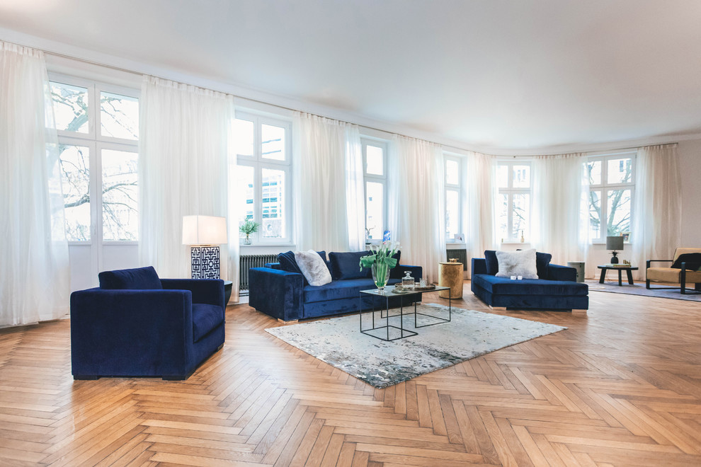 Large bohemian open plan games room in Berlin with medium hardwood flooring, white walls and brown floors.