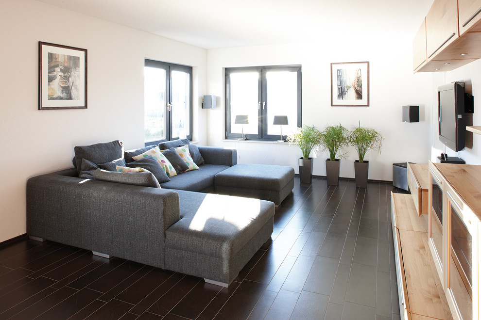 Diseño de sala de estar minimalista con paredes blancas, suelo de baldosas de terracota, televisor colgado en la pared y suelo marrón