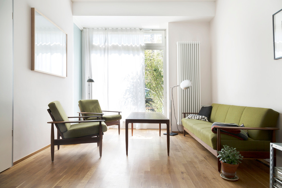 Mittelgroßes, Abgetrenntes Retro Wohnzimmer ohne Kamin mit weißer Wandfarbe und braunem Holzboden in Berlin
