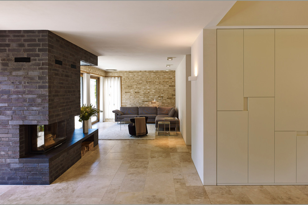 Пример оригинального дизайна: открытая гостиная комната в стиле модернизм с разноцветными стенами, полом из травертина, стандартным камином, фасадом камина из кирпича и бежевым полом