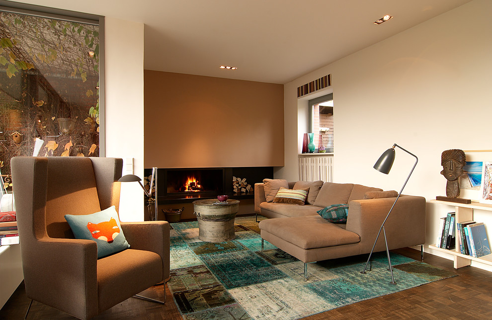 Foto de sala de estar abierta contemporánea de tamaño medio con paredes marrones, suelo de madera oscura, marco de chimenea de yeso y chimenea lineal