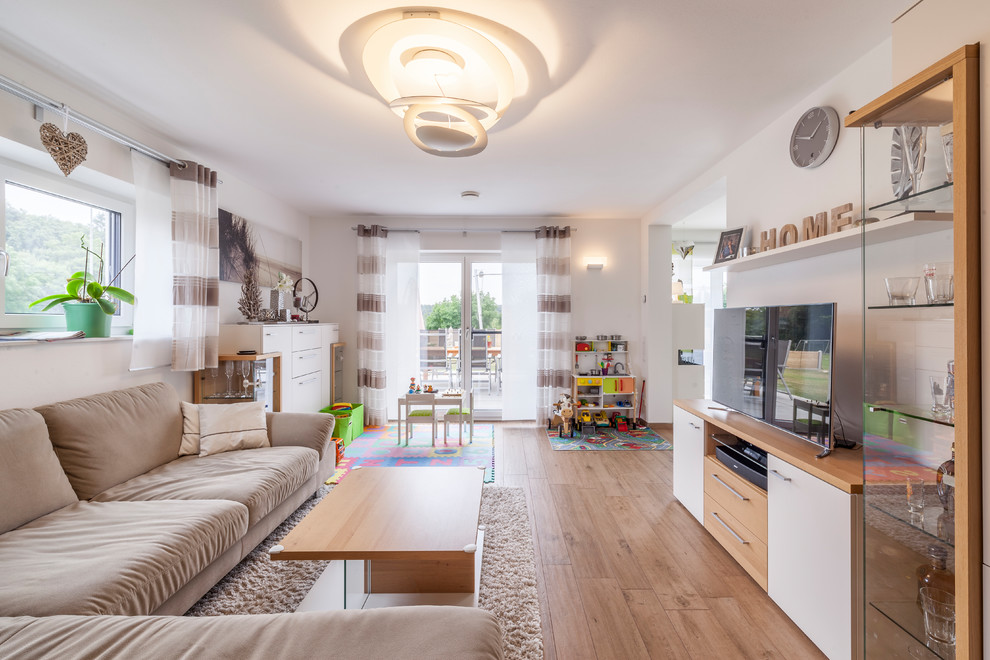 Mittelgroßes, Offenes Modernes Wohnzimmer ohne Kamin mit weißer Wandfarbe, braunem Holzboden, freistehendem TV und braunem Boden in Sonstige