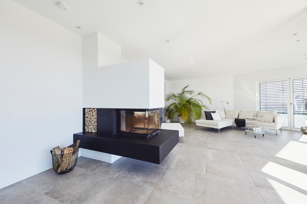 Inspiration pour une salle de séjour minimaliste de taille moyenne et ouverte avec un mur blanc, un sol en ardoise, une cheminée standard, un manteau de cheminée en plâtre et un sol gris.
