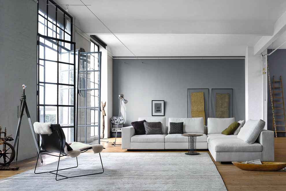 Foto de sala de estar abierta actual grande sin chimenea con paredes grises y suelo de madera en tonos medios