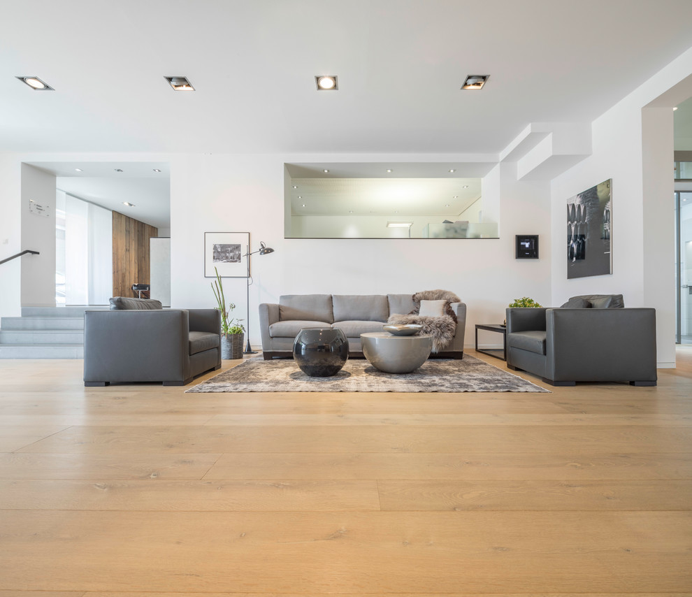 Ejemplo de sala de estar abierta contemporánea grande sin chimenea con paredes blancas, suelo de madera en tonos medios y suelo marrón