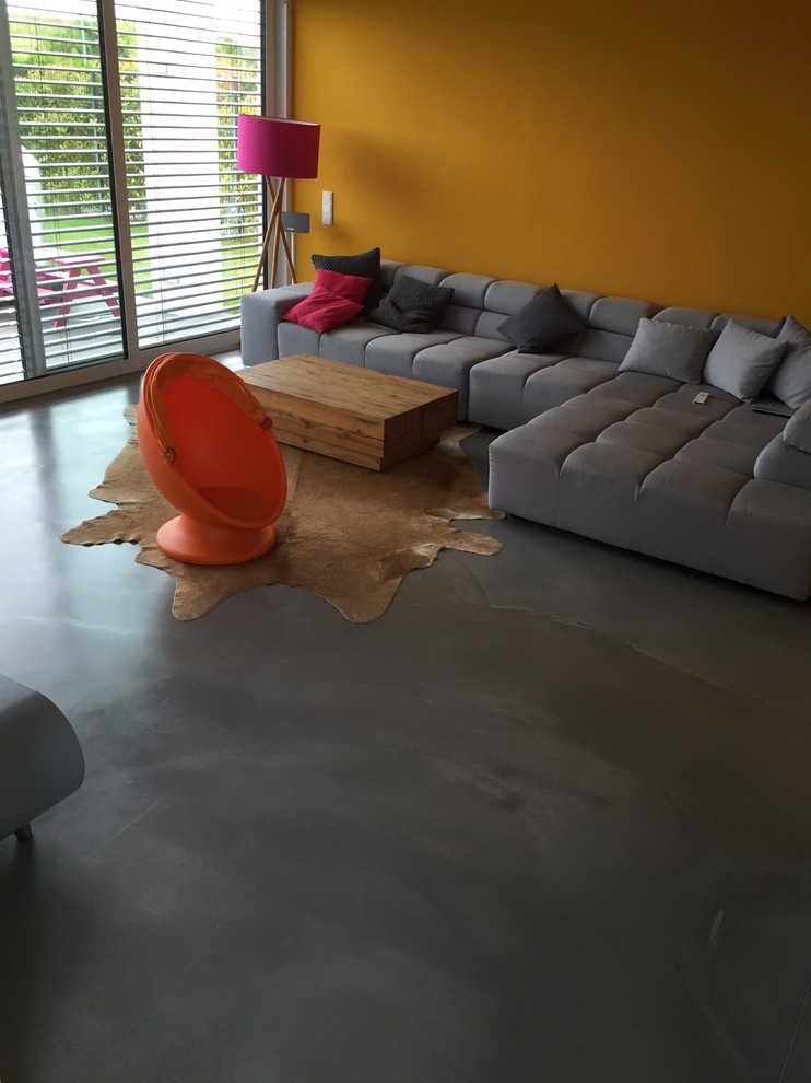 Design ideas for a large contemporary open plan games room in Cologne with a reading nook, yellow walls, concrete flooring and grey floors.