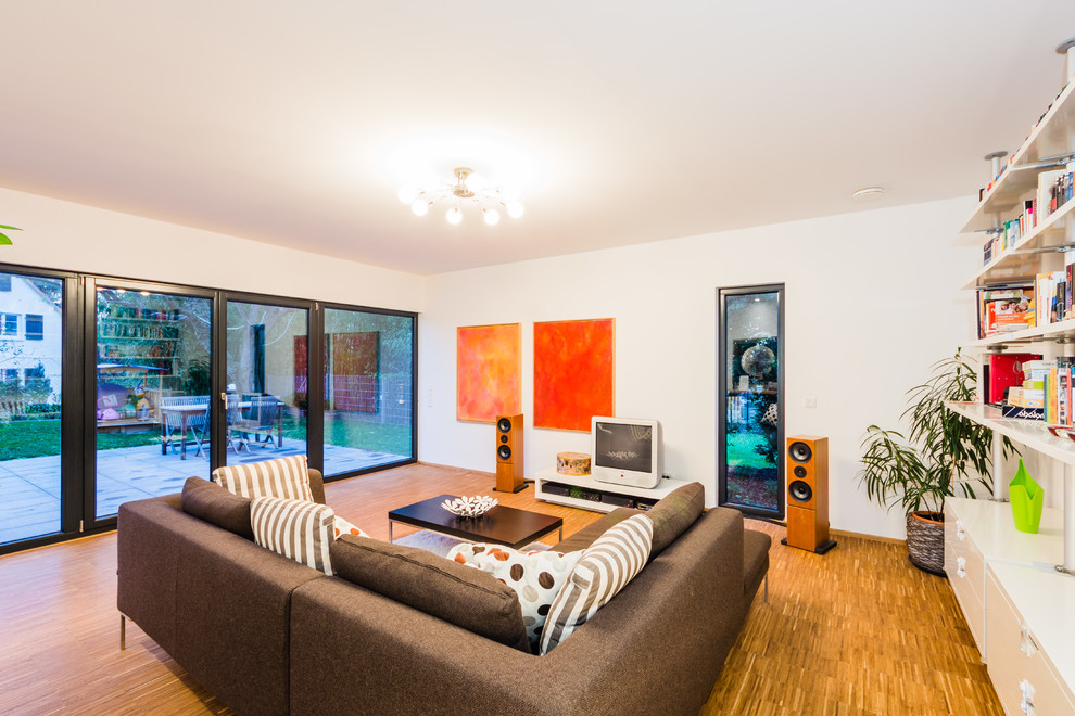 Mittelgroßes, Offenes Modernes Wohnzimmer mit braunem Holzboden und freistehendem TV in Frankfurt am Main