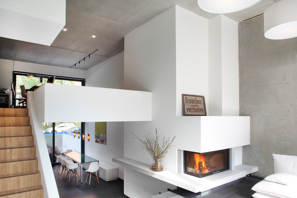 Imagen de salón abierto actual con paredes grises, marco de chimenea de yeso y chimenea lineal