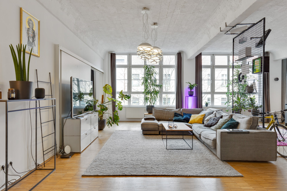 Immagine di un soggiorno bohémian aperto con pareti bianche, pavimento in legno massello medio, TV autoportante e pavimento marrone