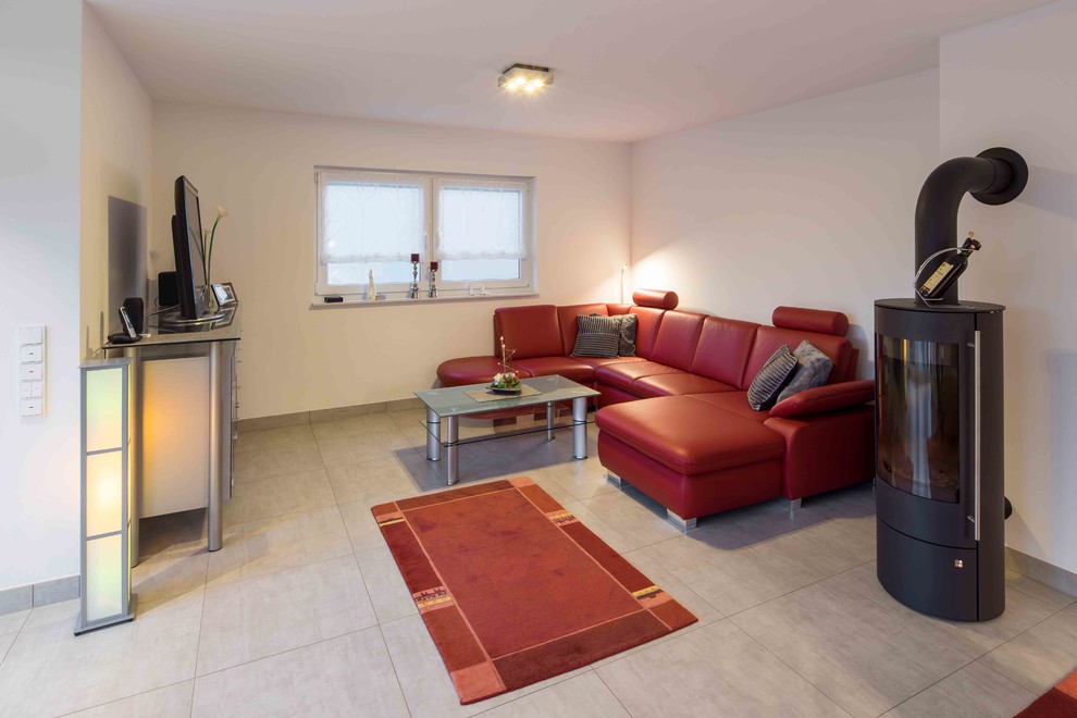 Diseño de sala de estar abierta actual con paredes blancas, estufa de leña, marco de chimenea de metal y suelo beige