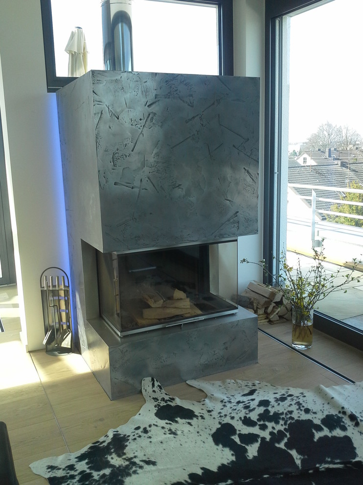 シュトゥットガルトにあるコンテンポラリースタイルのおしゃれなファミリールーム (標準型暖炉、金属の暖炉まわり) の写真