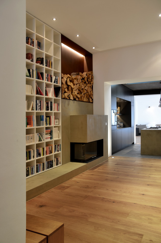 Offenes Modernes Wohnzimmer mit weißer Wandfarbe, hellem Holzboden, Eckkamin und Kaminumrandung aus Beton in Köln