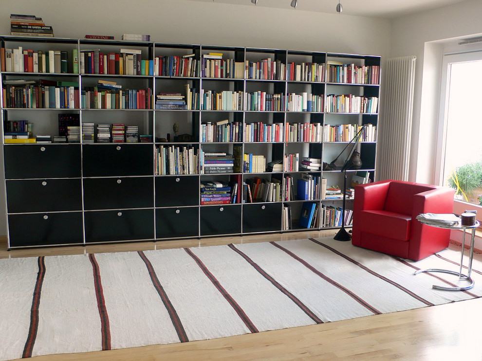 На фото: большая изолированная гостиная комната в скандинавском стиле с с книжными шкафами и полками, белыми стенами и светлым паркетным полом с