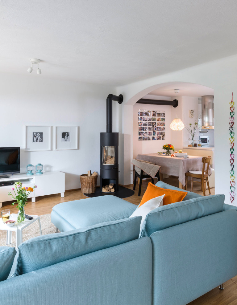 Foto di un soggiorno nordico di medie dimensioni e aperto con pareti arancioni, parquet chiaro, stufa a legna, TV autoportante e pavimento marrone