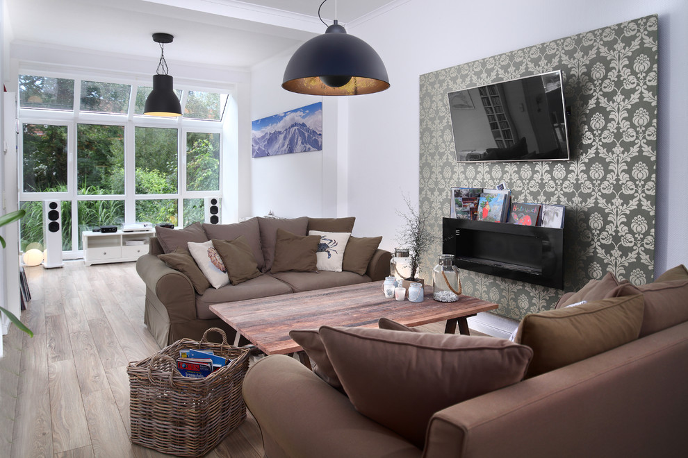 Modelo de sala de estar cerrada marinera de tamaño medio con paredes blancas, suelo de madera clara, televisor colgado en la pared y suelo beige