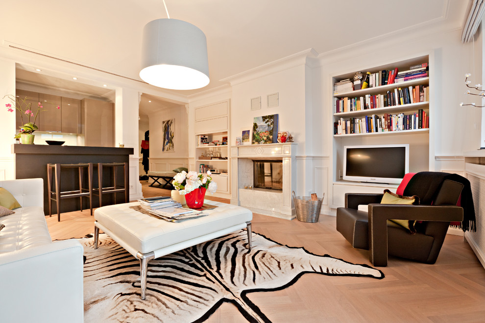 Imagen de sala de estar abierta tropical grande con paredes blancas, suelo de madera clara, todas las chimeneas y televisor independiente