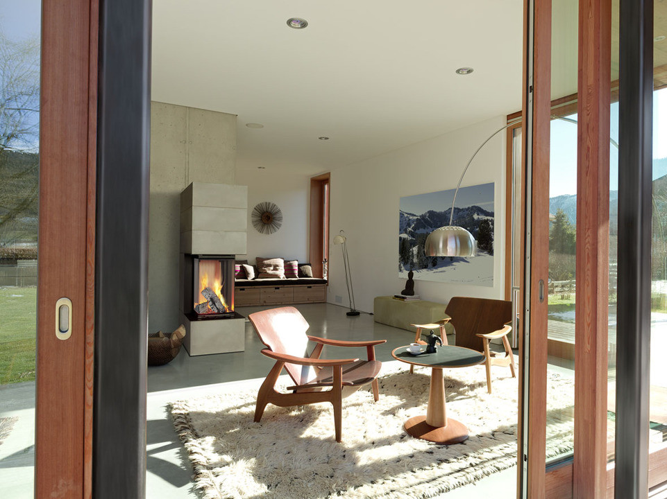 Immagine di un soggiorno contemporaneo di medie dimensioni e aperto con camino classico e cornice del camino in cemento