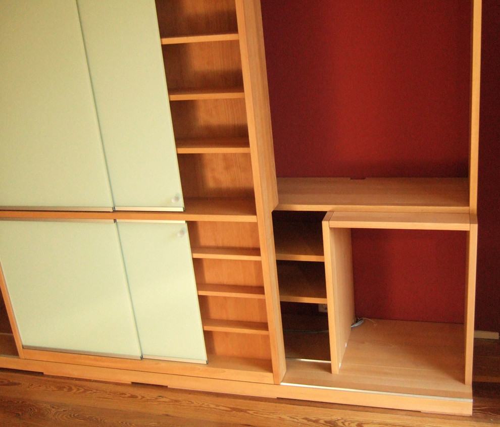 Imagen de biblioteca en casa cerrada contemporánea de tamaño medio con paredes blancas, suelo de madera clara y suelo marrón