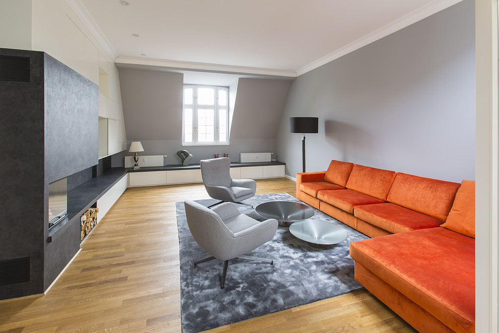 Cette photo montre un grand salon tendance ouvert avec un mur gris, un sol en bois brun et une salle de réception.