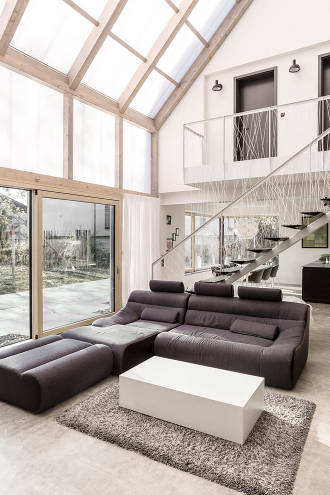 На фото: огромная двухуровневая гостиная комната в стиле модернизм с бетонным полом, белыми стенами и серым полом без камина, телевизора