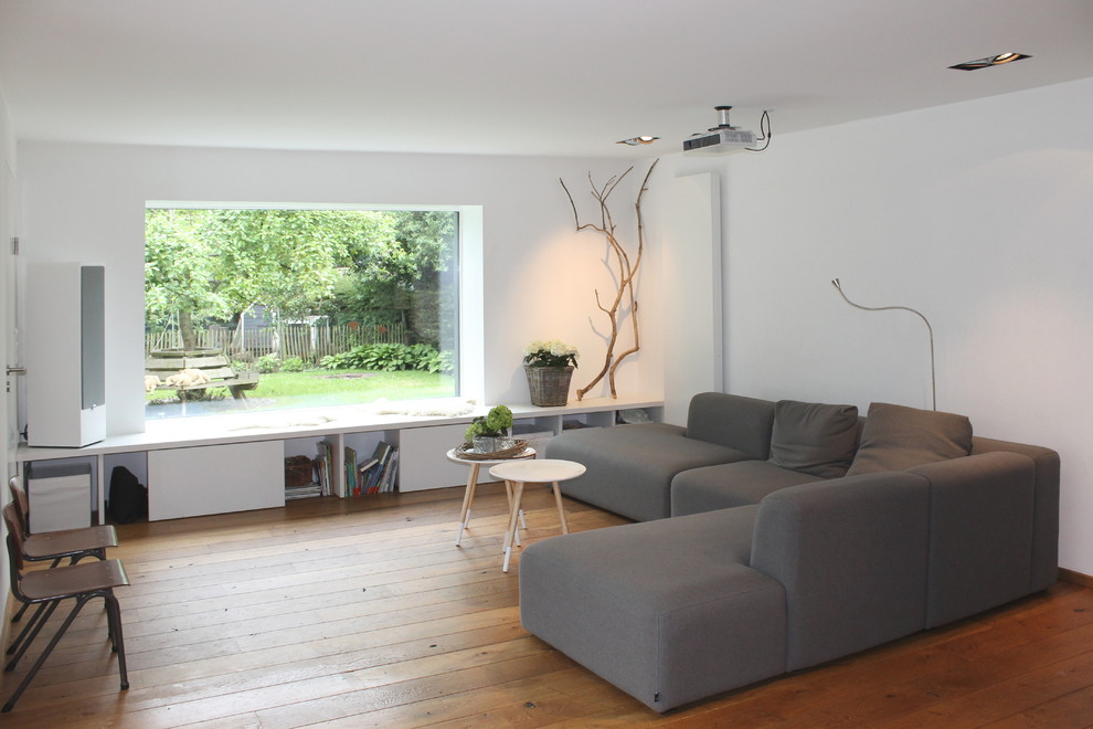 Example of a mid-sized danish medium tone wood floor family room design in Other with white walls and no fireplace
