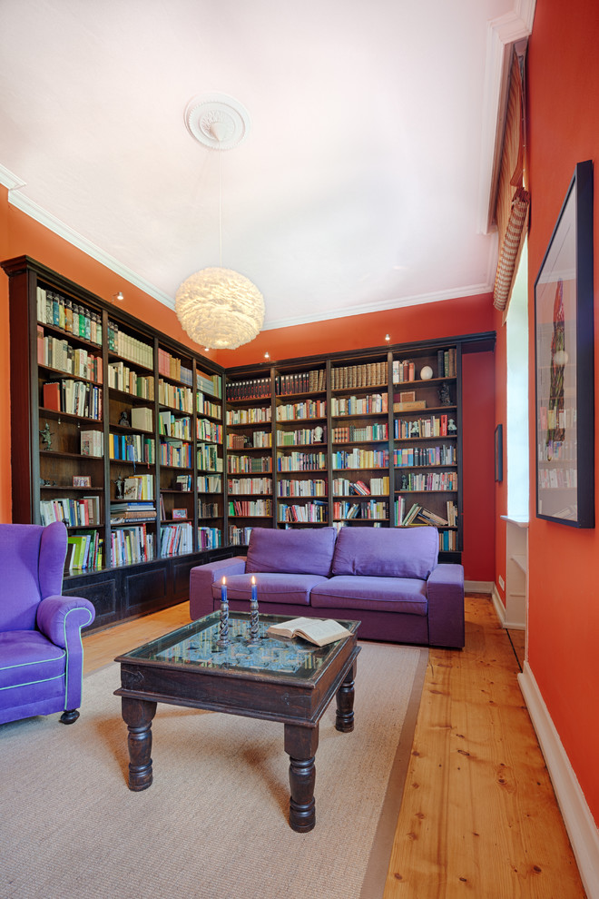 Exempel på ett mellanstort eklektiskt separat vardagsrum, med orange väggar, mörkt trägolv, brunt golv och ett bibliotek