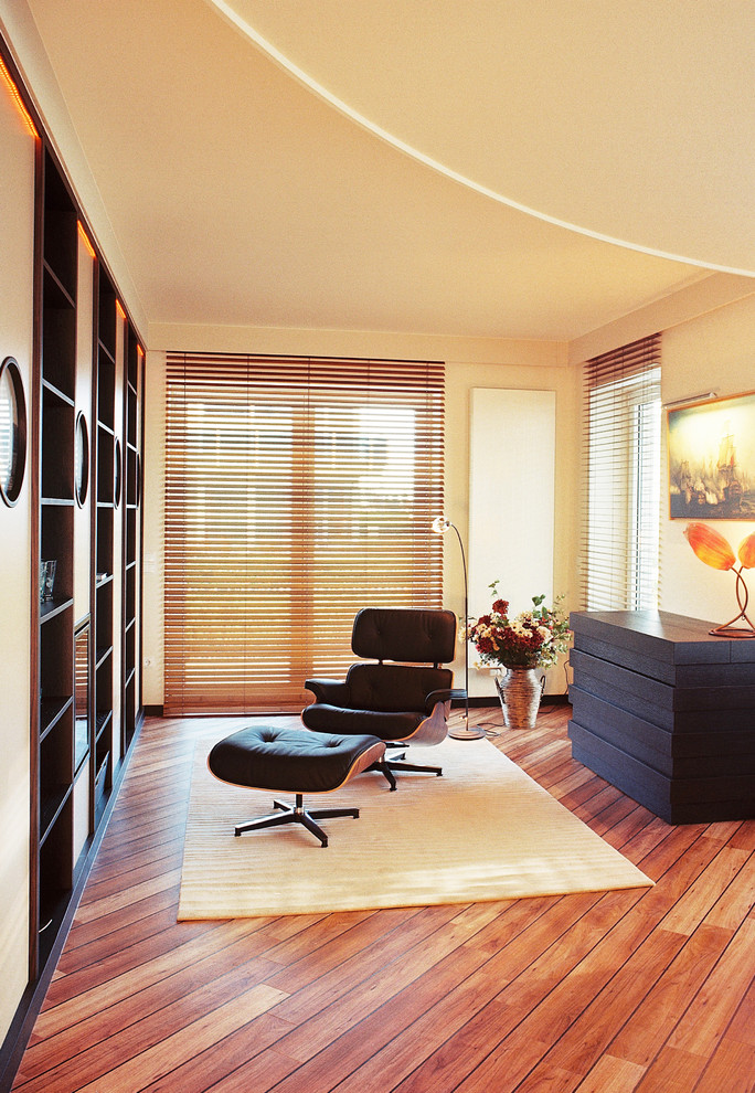 Inspiration pour une grande salle de séjour design ouverte avec un mur jaune, un sol en bois brun, une cheminée standard, un manteau de cheminée en plâtre, un téléviseur dissimulé et un sol marron.