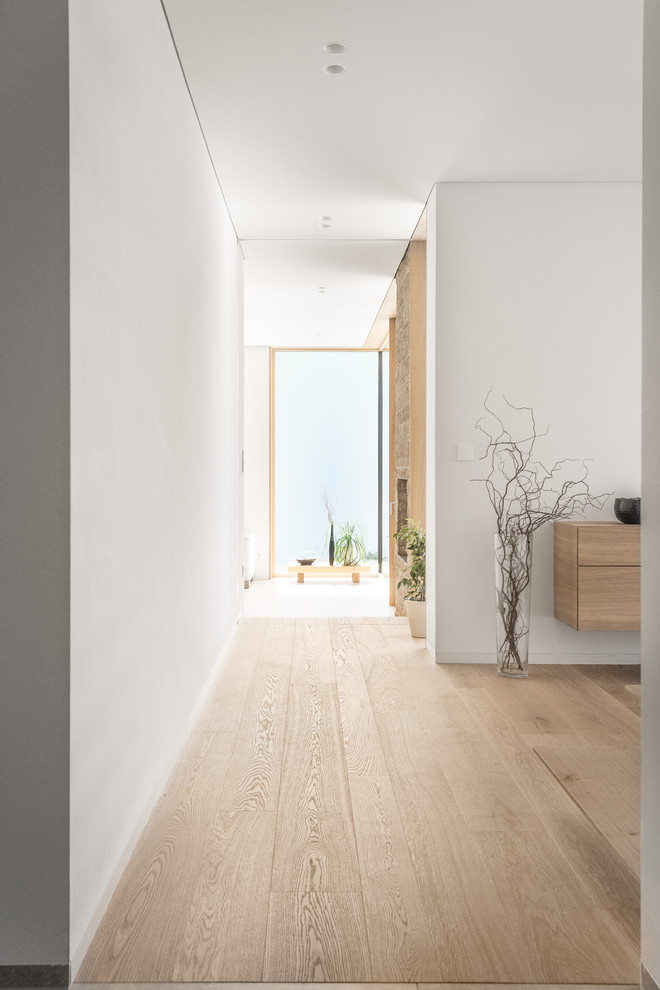 Foto de salón para visitas abierto minimalista extra grande con paredes blancas, suelo de madera clara, chimenea de doble cara, marco de chimenea de piedra y suelo beige