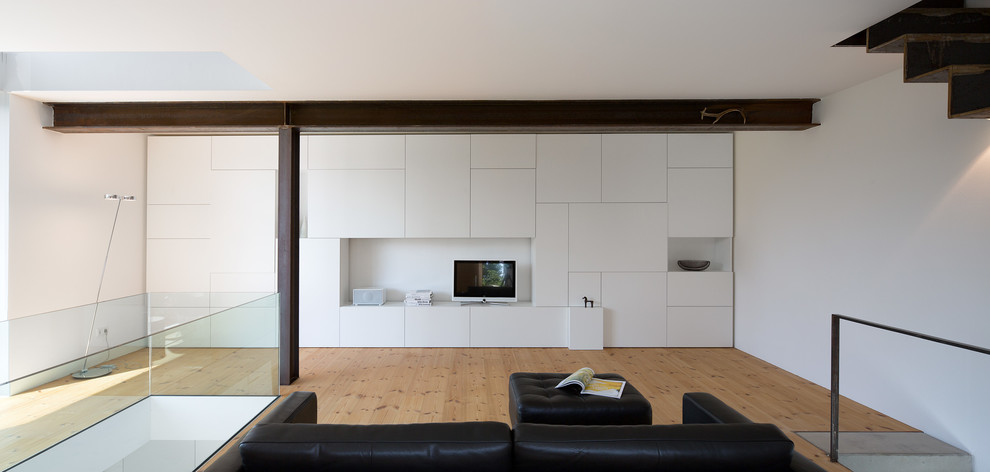 Offenes, Mittelgroßes Modernes Wohnzimmer mit weißer Wandfarbe, freistehendem TV, braunem Boden und hellem Holzboden in München