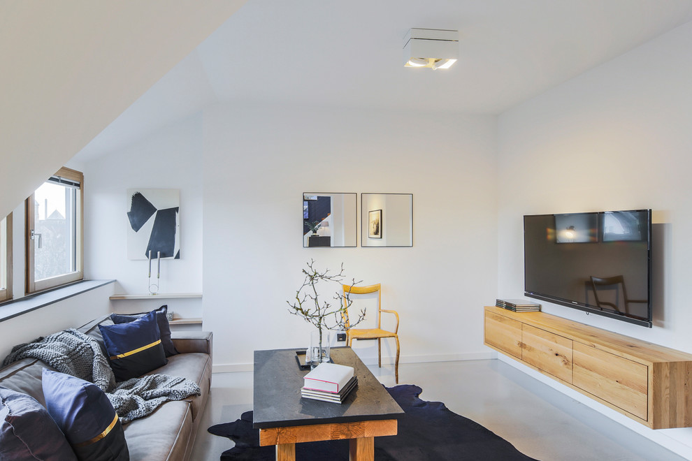 Cette image montre une salle de séjour design de taille moyenne avec un mur blanc, sol en béton ciré, un téléviseur fixé au mur et un sol gris.
