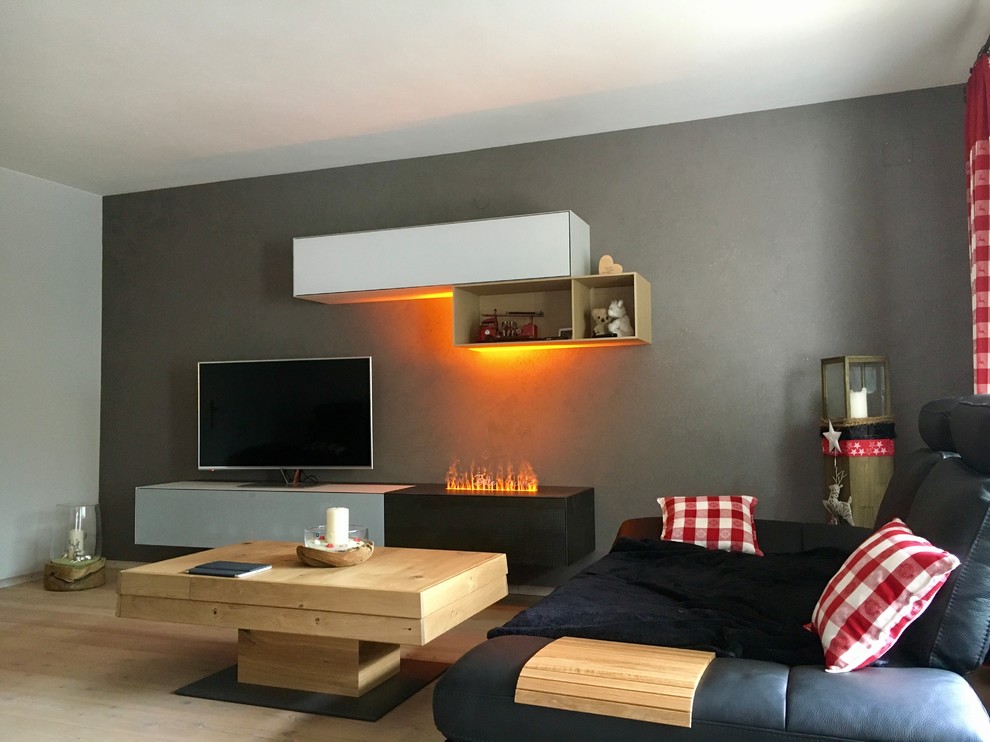 Cette image montre une petite salle de séjour design ouverte avec parquet peint, un téléviseur encastré, un sol beige et un mur gris.