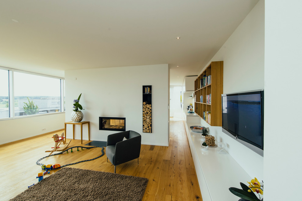 Großes, Offenes Modernes Wohnzimmer mit weißer Wandfarbe, braunem Holzboden, Tunnelkamin, TV-Wand und verputzter Kaminumrandung in Sonstige