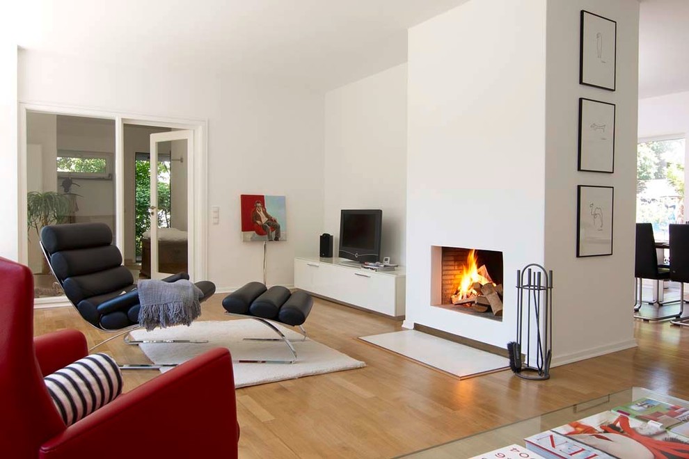 Inspiration for a large contemporary open concept medium tone wood floor living room remodel in Hanover with white walls, a standard fireplace, a plaster fireplace and a tv stand