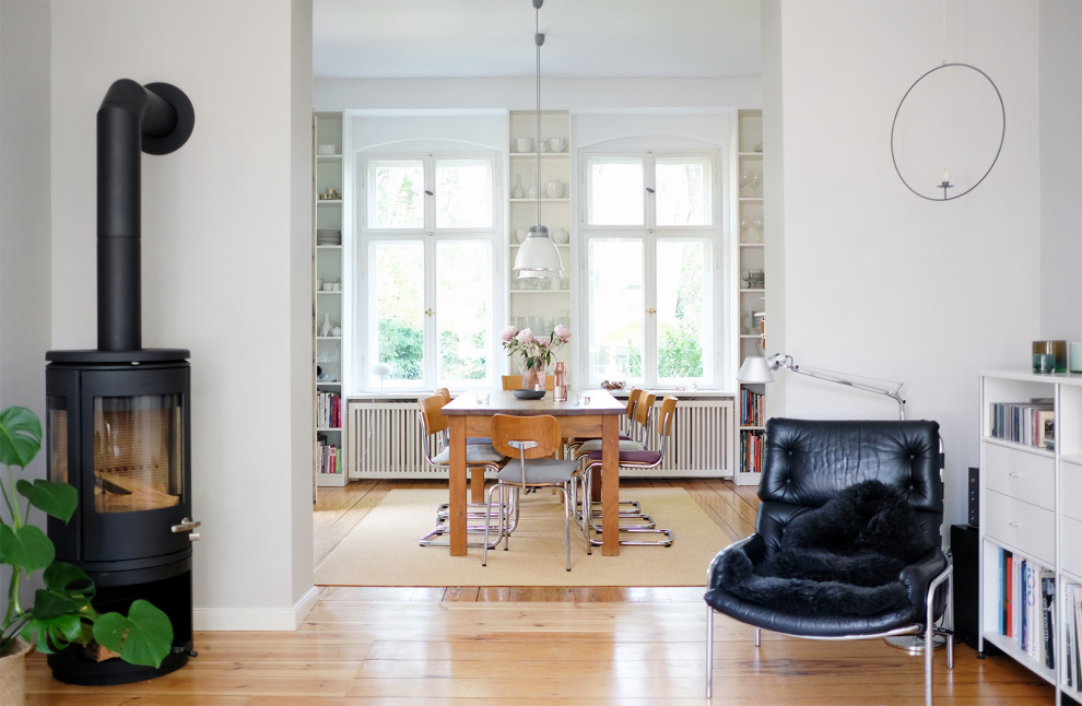 Offenes Modernes Wohnzimmer mit grauer Wandfarbe, hellem Holzboden und Kaminofen in Berlin