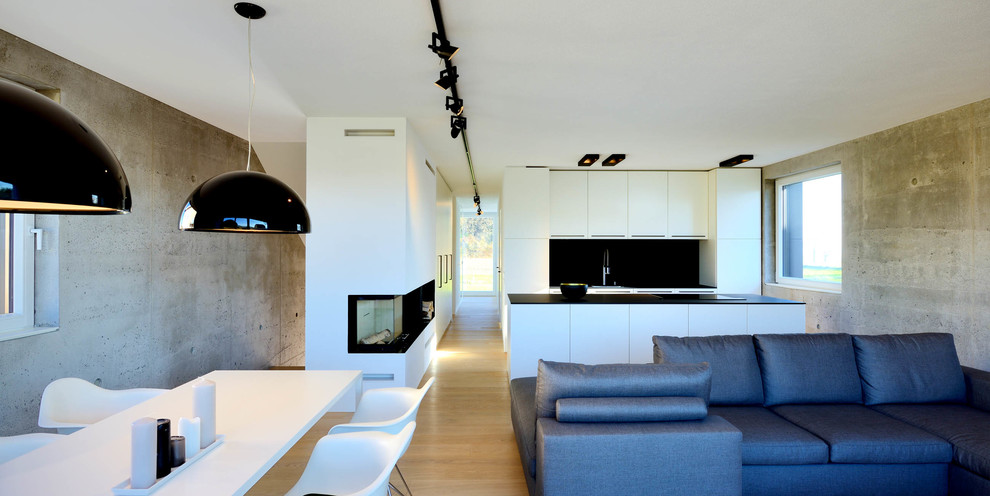 Offenes Modernes Wohnzimmer mit grauer Wandfarbe, hellem Holzboden, Eckkamin und verputzter Kaminumrandung in München