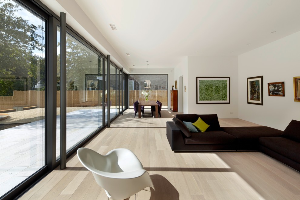 Example of a large trendy open concept light wood floor living room design in Dusseldorf with white walls