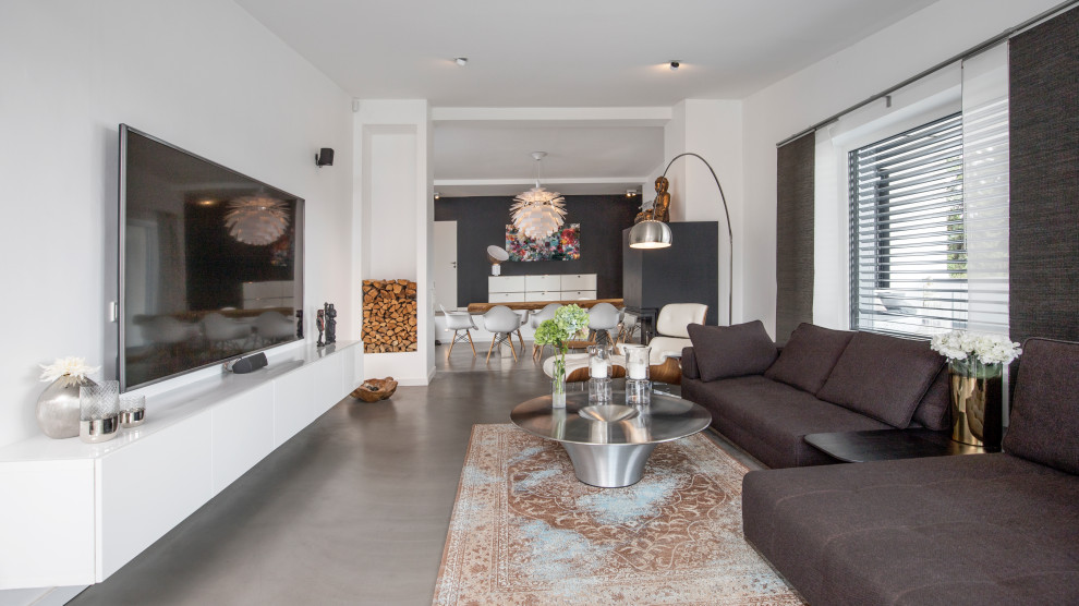This is an example of a large contemporary living room in Dortmund with white walls, a wall mounted tv and grey floors.