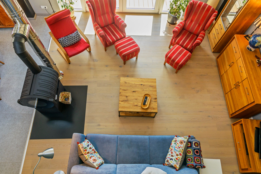 Großes, Offenes Modernes Wohnzimmer mit grauer Wandfarbe, braunem Holzboden, Kaminofen, freistehendem TV und braunem Boden in Hamburg
