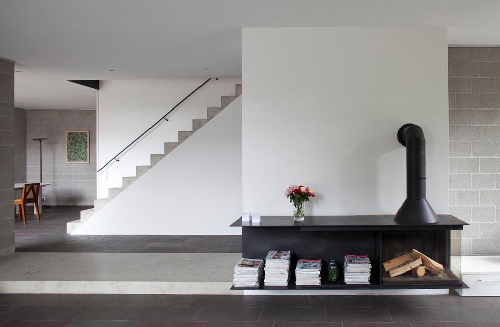 На фото: открытая гостиная комната в современном стиле с серыми стенами, печью-буржуйкой и фасадом камина из металла с