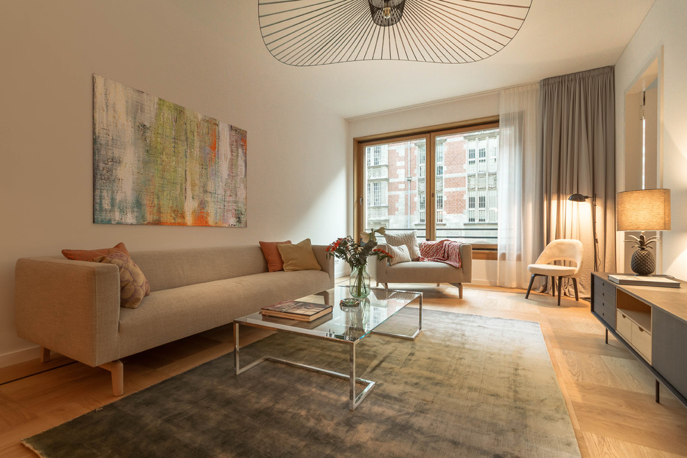 Modelo de sala de estar abierta actual de tamaño medio sin chimenea con paredes blancas, suelo de madera en tonos medios, suelo marrón y televisor independiente
