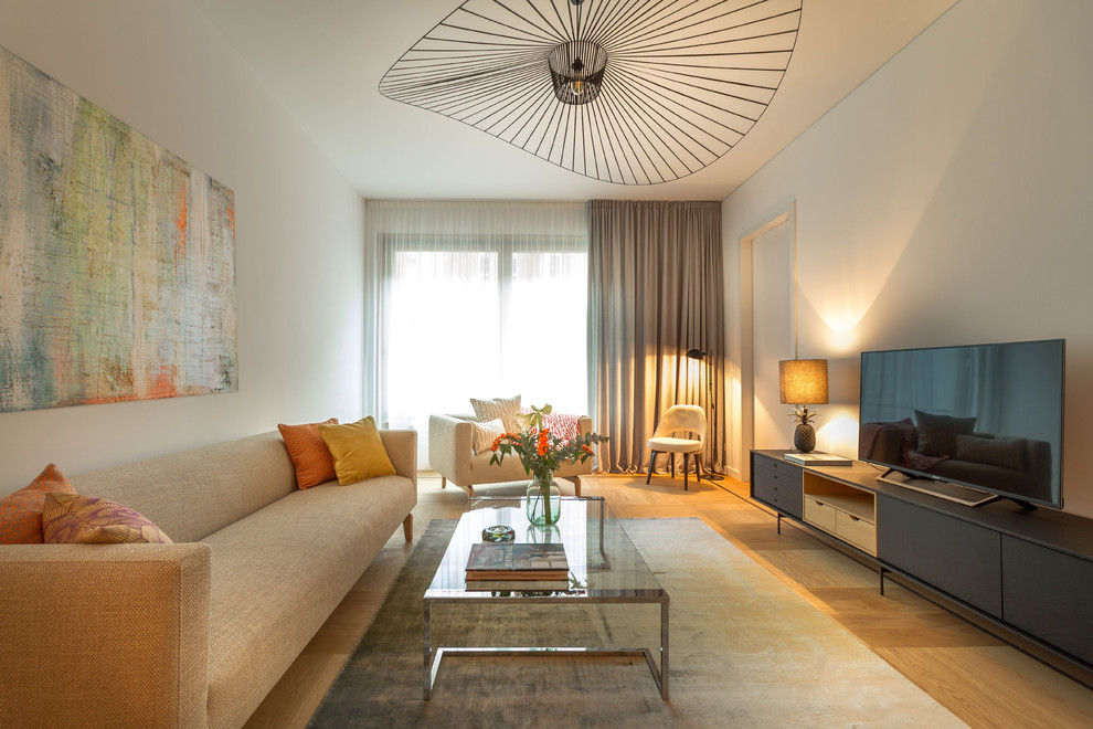 Mittelgroßes, Offenes Modernes Wohnzimmer ohne Kamin mit weißer Wandfarbe, braunem Holzboden, freistehendem TV und braunem Boden in Berlin