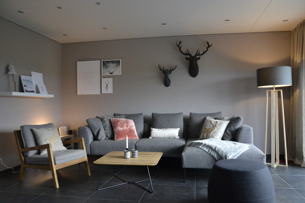 Пример оригинального дизайна: открытая гостиная комната среднего размера в скандинавском стиле с серыми стенами, полом из керамической плитки, печью-буржуйкой, фасадом камина из плитки, телевизором на стене и серым полом
