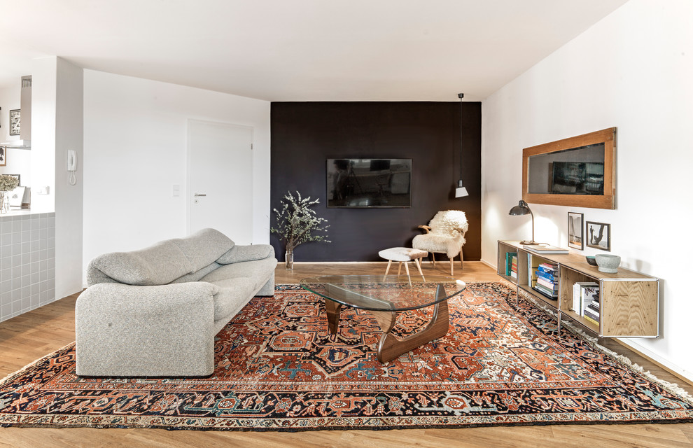 Family room library - mid-sized eclectic loft-style medium tone wood floor and brown floor family room library idea in Hamburg with black walls, a wall-mounted tv and no fireplace