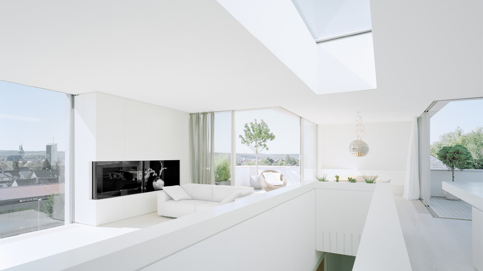 Источник вдохновения для домашнего уюта: огромная открытая гостиная комната в современном стиле с белыми стенами, светлым паркетным полом и телевизором на стене без камина