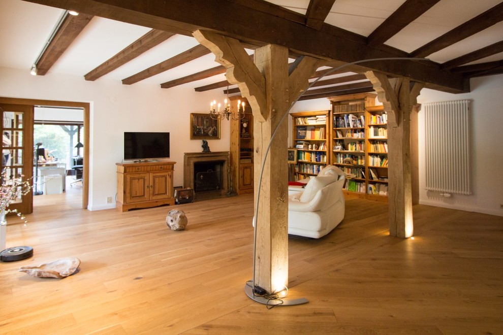 Immagine di un grande soggiorno rustico aperto con libreria, pareti bianche, parquet chiaro, TV autoportante e pavimento marrone