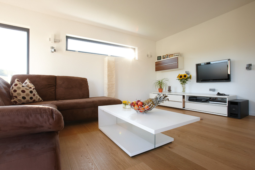 Idee per un soggiorno minimal con pareti bianche, parquet chiaro, TV a parete e pavimento marrone
