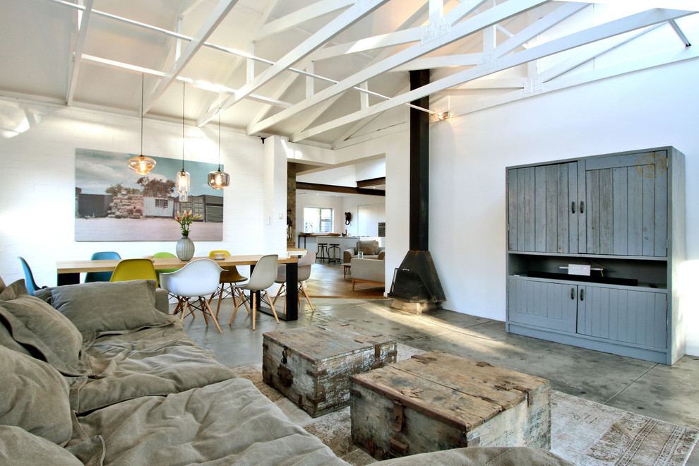 This is an example of an urban open plan living room in Berlin with white walls, concrete flooring and a wood burning stove.