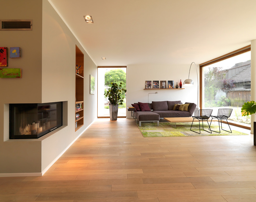 Inspiration pour une grande salle de séjour design ouverte avec un mur beige, un sol en bois brun et une cheminée d'angle.