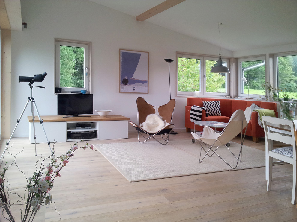 Imagen de salón abierto nórdico grande con paredes blancas, suelo de madera clara y televisor independiente